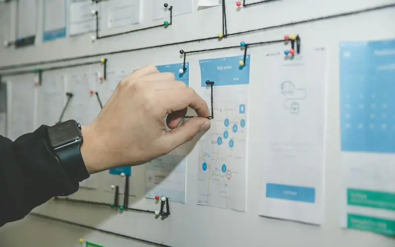 A person mapping a workflow on a wall board