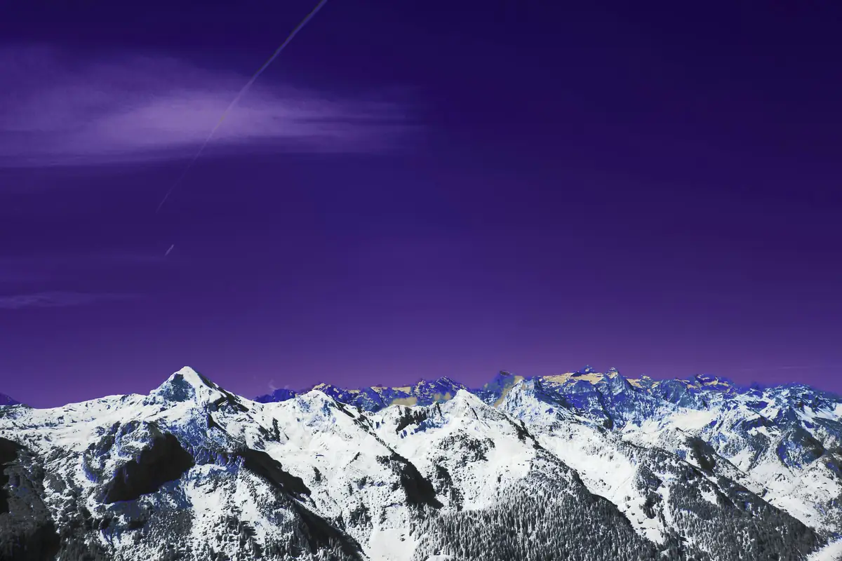 Snow-covered mountains under a deep violet sky